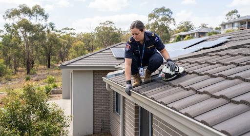 Firefighter inspecting clean house roof edge for bushfire safety compliance in New South Wales Australia