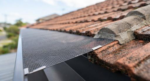 Macro close-up of professional aluminium mesh gutter guard fitted cleanly over tile roof edge